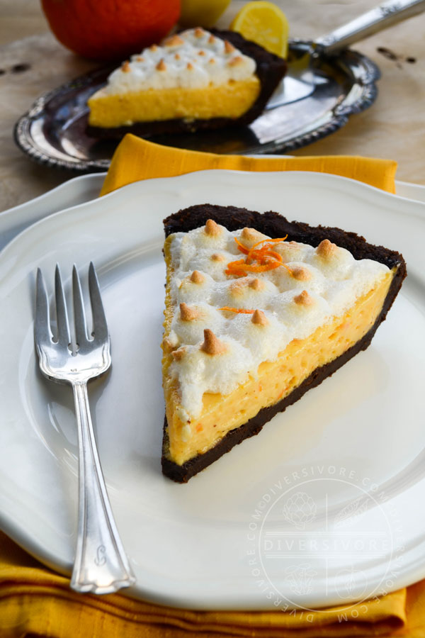 A slice of seville orange pie with meringue and a chocolate graham wafer crust, served on a white plate with a silver dessert fork