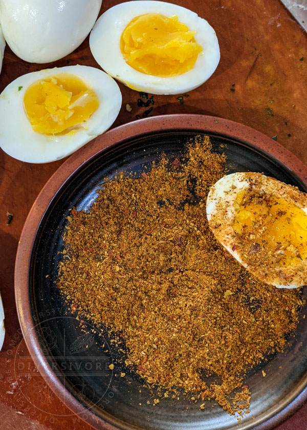 Boiled eggs being dipped in salt and biryani masala before frying